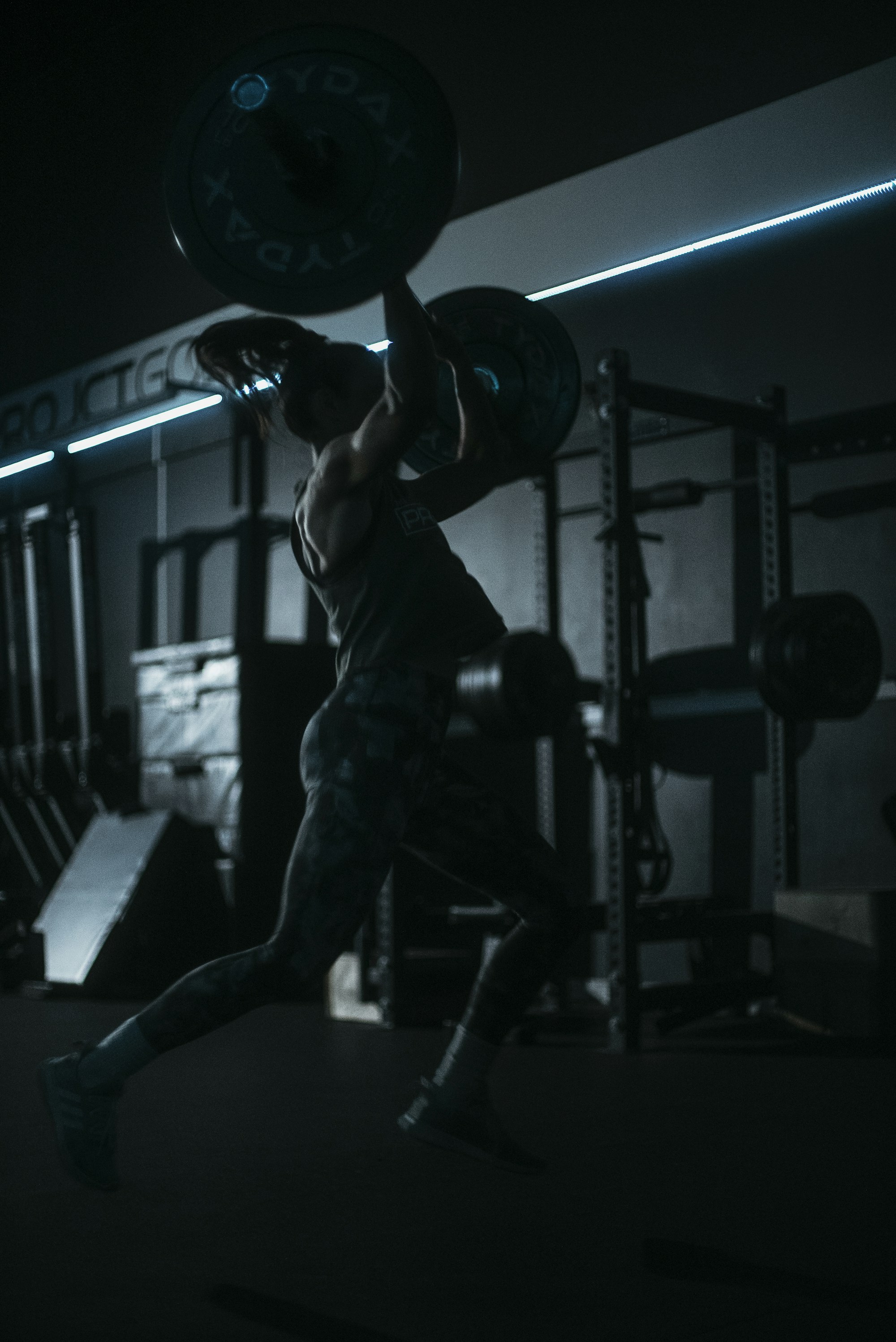 Athlete lifting a barbell in a dark gym